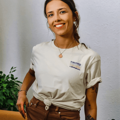 Eine lachende Frau im beigen Urban T-Shirt. Am Bauch hat das Shirt ein Knoten