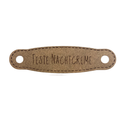 Hier ist das Etikett mit der Schrift "Feste Nachtcreme" zu sehen. Es ist eine ovale Form mit zwei Löcher an der linken und rechten Seite.