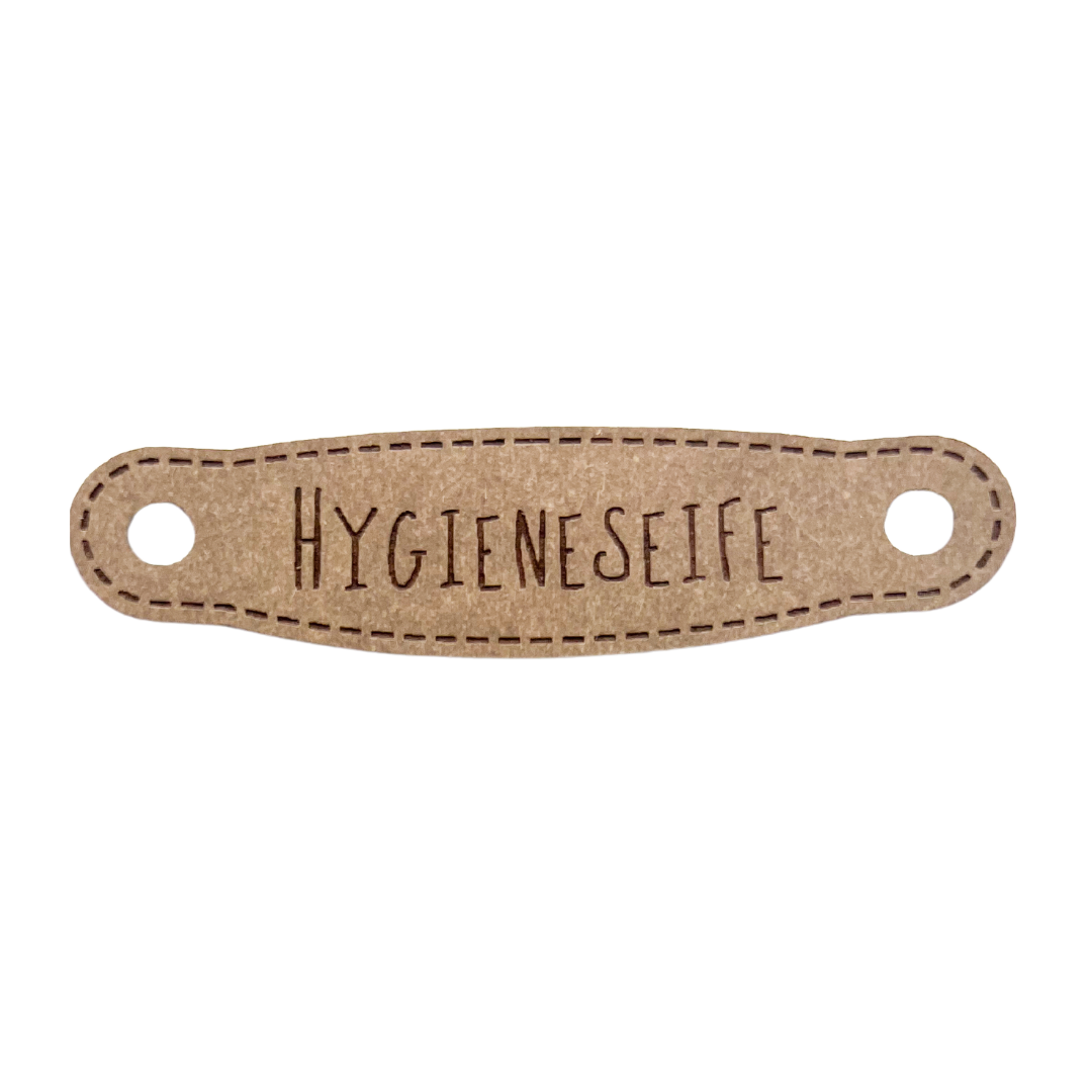Hier ist das Etikett mit der Schrift "Hygieneseife" zu sehen. Es ist eine ovale Form mit zwei Löcher an der linken und rechten Seite.