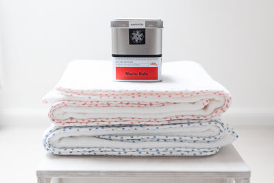 Zwei decken aufeinander. Oben die Rote und unten eine blaue Decke. Oben drauf steht eine silberne Aluminiumdose in der Tee der Sorte Maybe Baby steht.