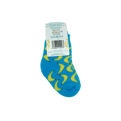 Vollbild der blauen Kindersocken mit Bananenmuster. Oben an der Socke ist ein Schild auf der ein Barcode, sowie allgemeine Infos über die Socken.
